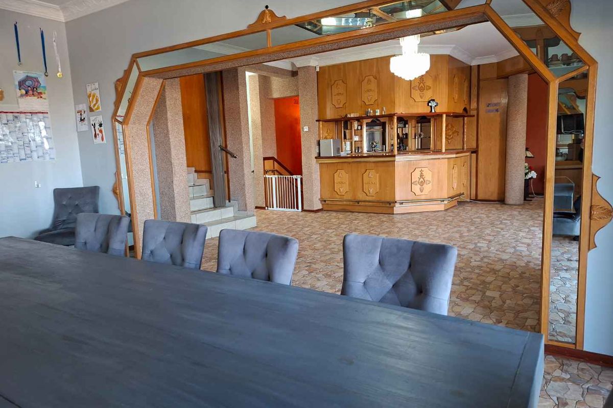 Spacious living area featuring a built-in wooden bar, decorative mirror framing, and tiled flooring, offering a versatile space for entertaining.