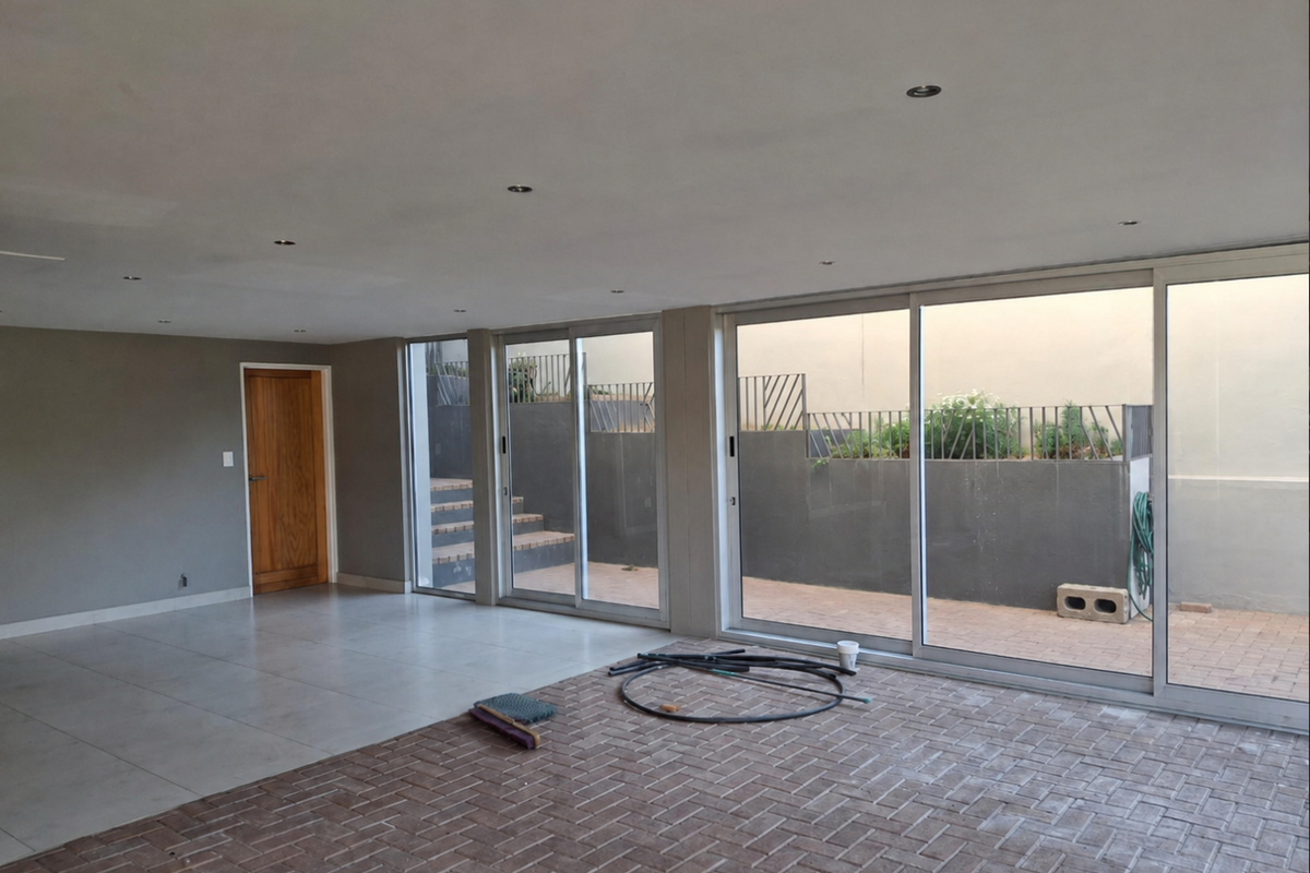Spacious open-plan living area featuring large sliding glass doors, recessed lighting, and a combination of tiled and brick paver flooring.