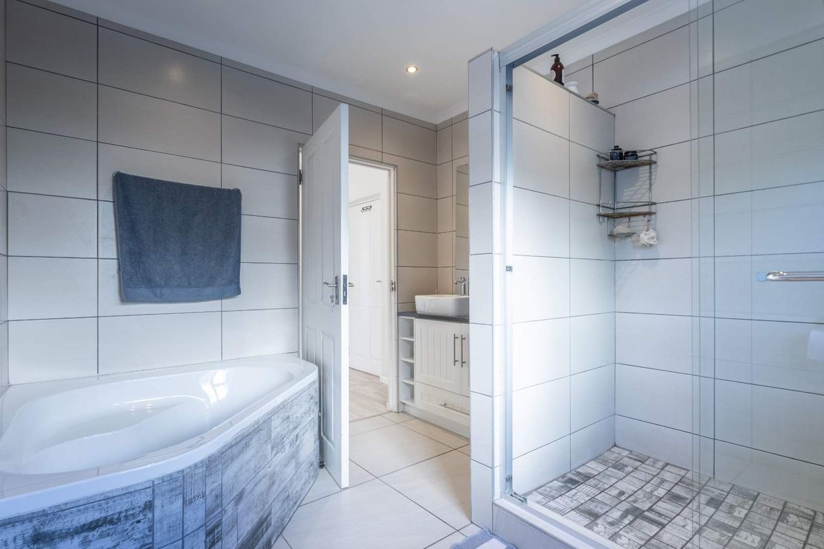 Modern bathroom featuring a corner bathtub, a separate glass-enclosed shower, and a vanity unit with a vessel sink.