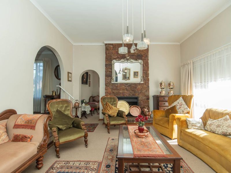 A cozy living room featuring a prominent stone fireplace, classic archways, and neutral wall finishes, offering a warm and traditional atmosphere.