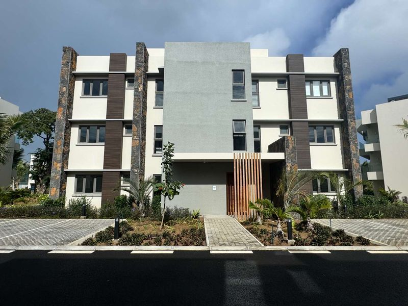Modern apartment building facade featuring stone cladding, timber accents, and a paved entrance walkway with landscaped garden beds.