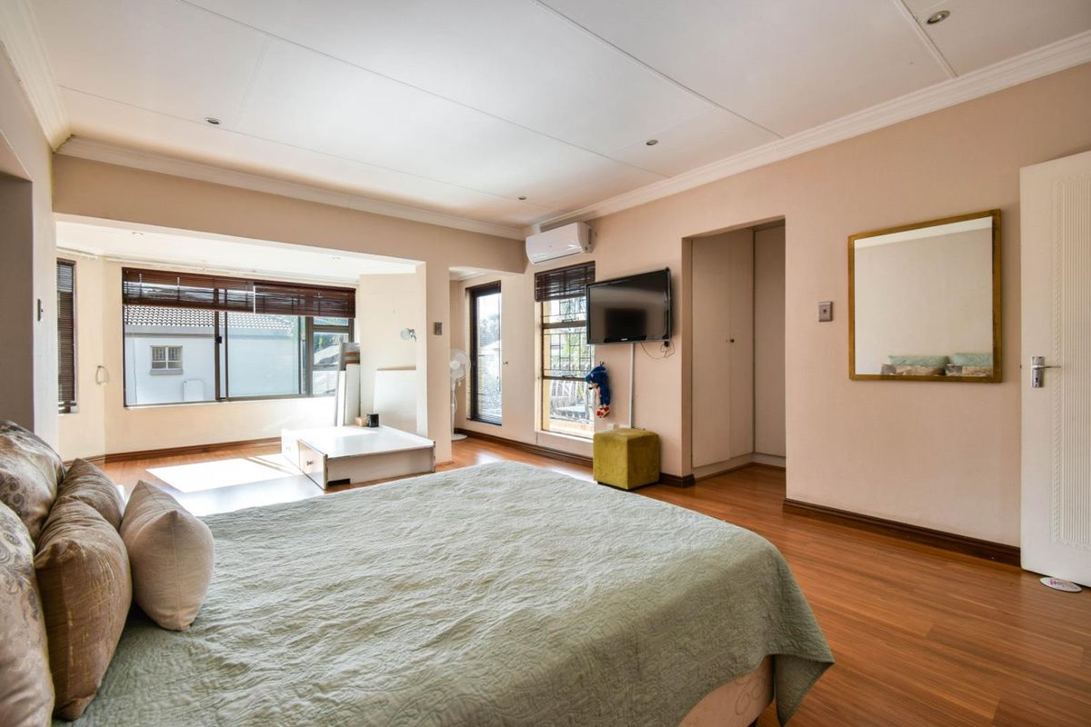 Spacious bedroom featuring laminate flooring, recessed ceiling lighting, built-in storage, and an integrated air conditioning unit.