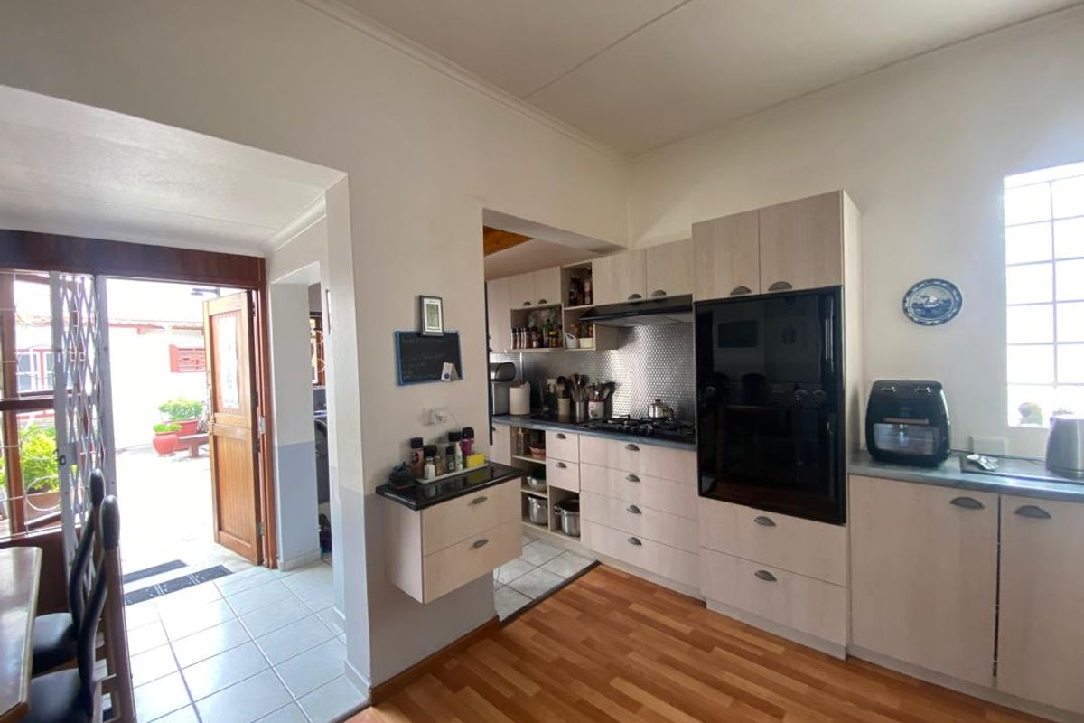 Functional kitchen featuring light-toned cabinetry, built-in oven, gas hob, and extractor fan, with direct access to an outdoor patio area.