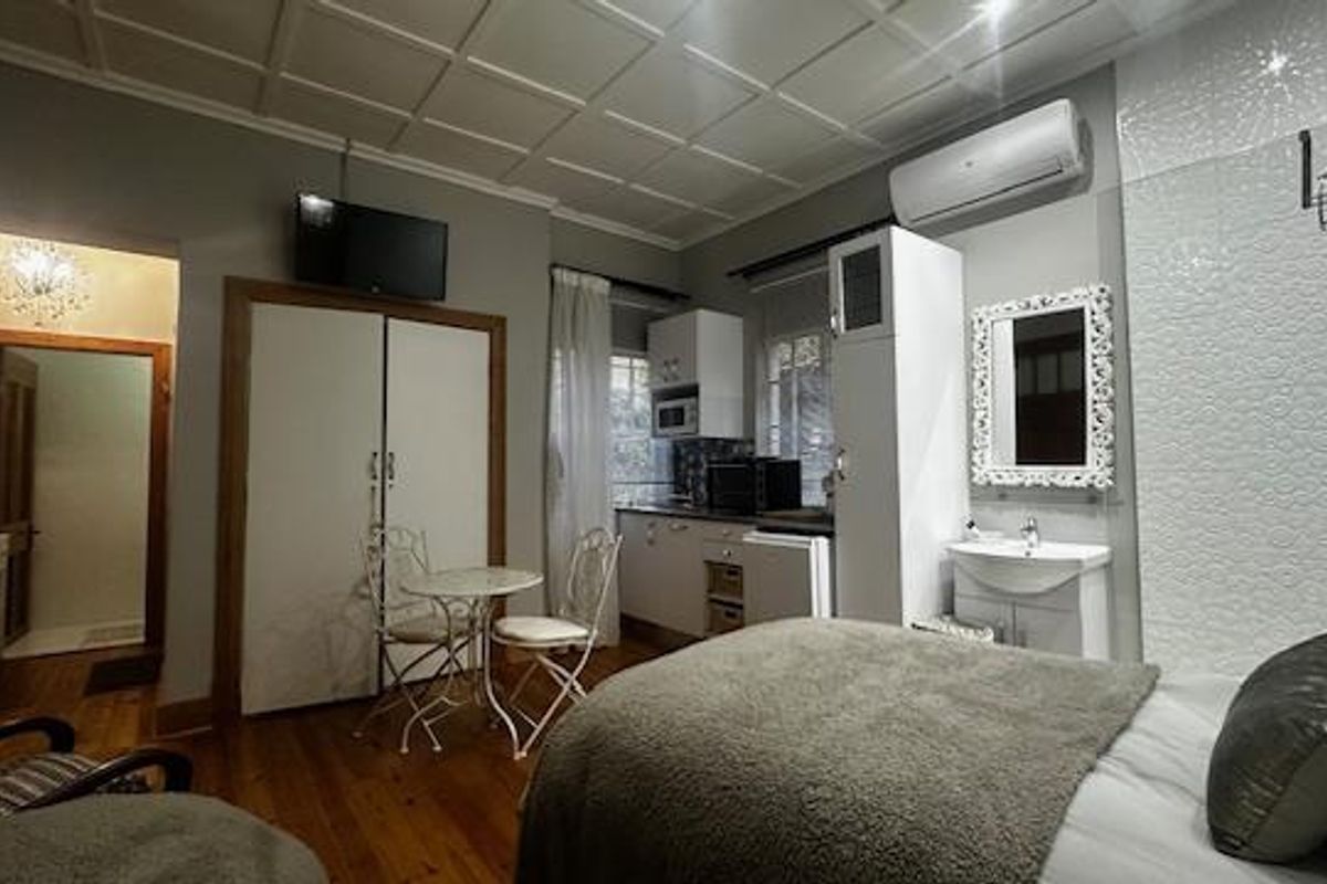 A well-maintained bedroom featuring timber flooring, a coffered ceiling, integrated vanity basin, and built-in storage with an air conditioning unit.