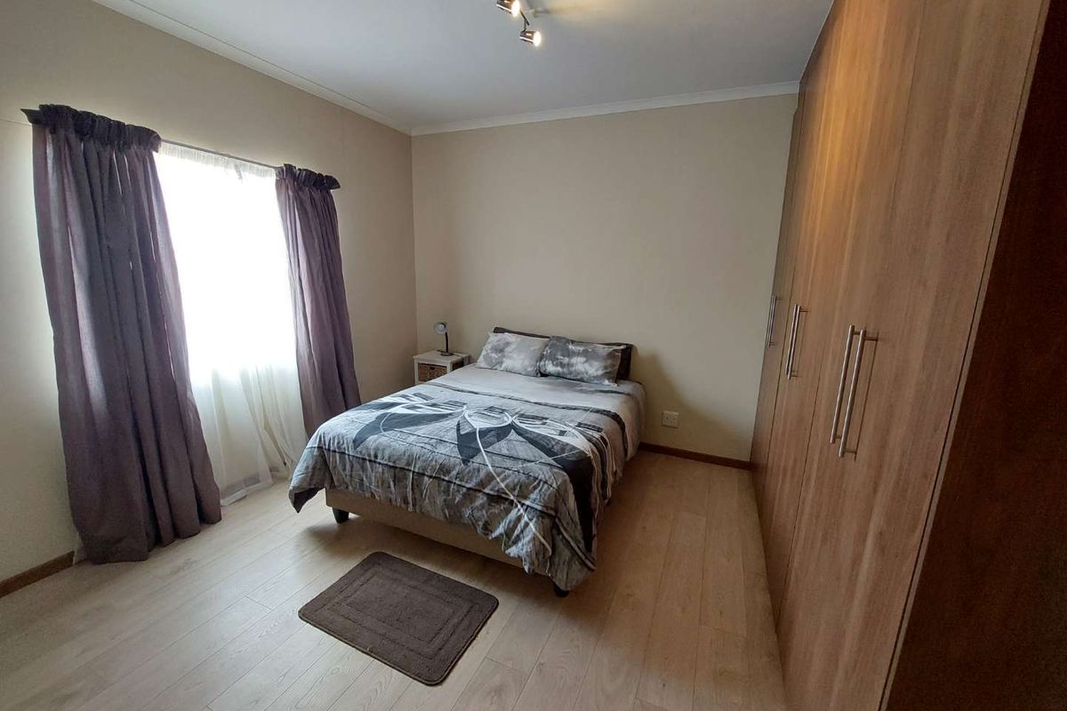 A well-maintained bedroom featuring light wood-look laminate flooring and extensive built-in wooden cabinetry providing ample storage space.