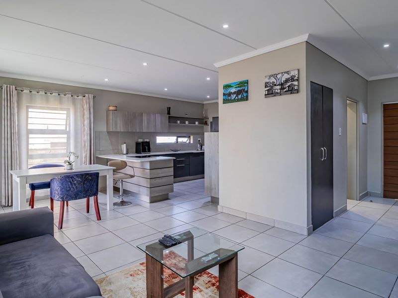 Spacious open-plan living area featuring tiled floors, recessed lighting, and a modern kitchen with built-in cabinetry and a central island.