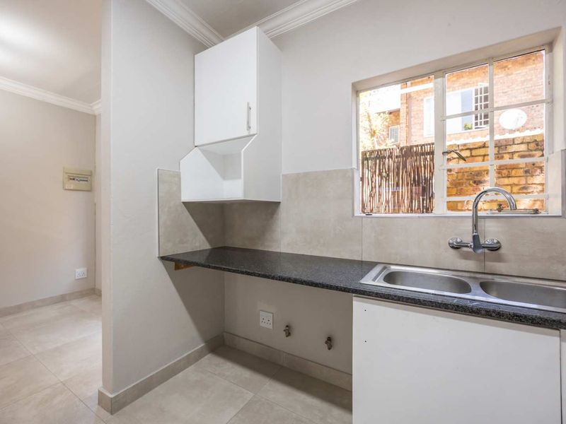A clean and functional scullery area featuring a double basin sink, granite countertops, tiled backsplash, and dedicated plumbing connections for appliances.