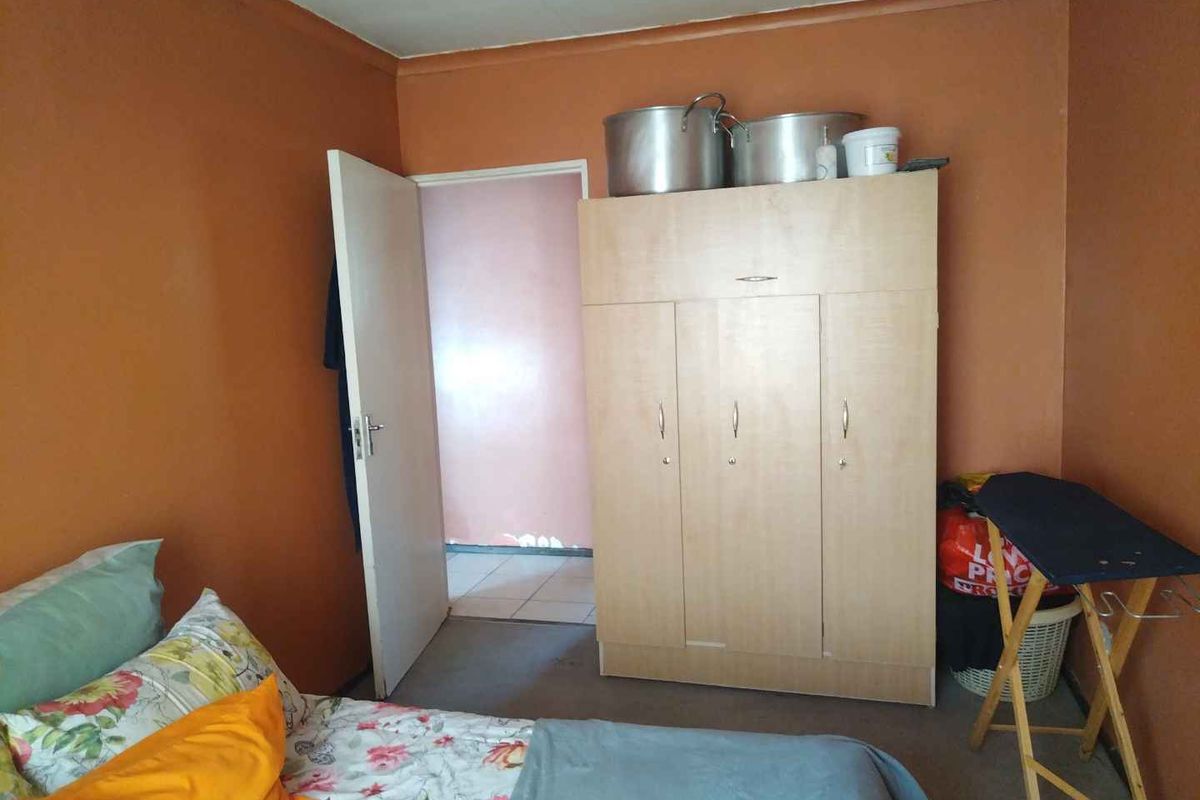 A bedroom featuring orange painted walls and a standard door leading to an adjacent room.