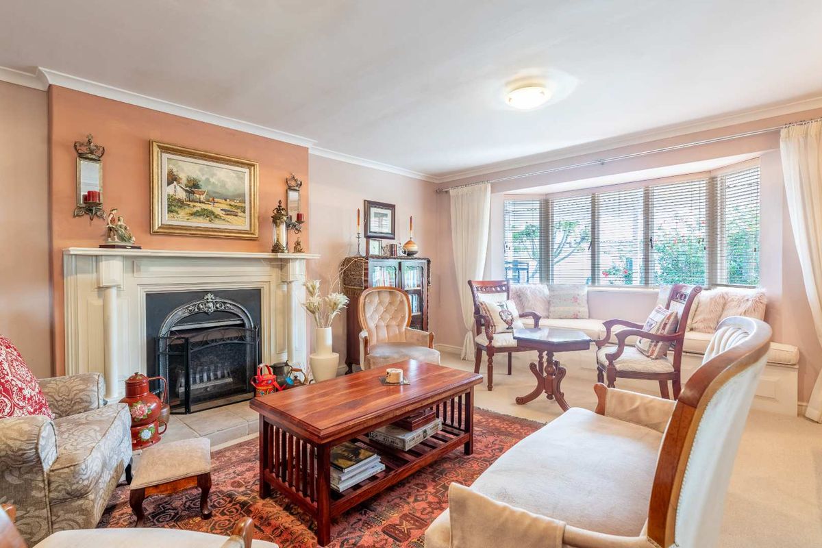 A traditional living room featuring a classic fireplace with a mantelpiece and a large bay window with built-in seating.