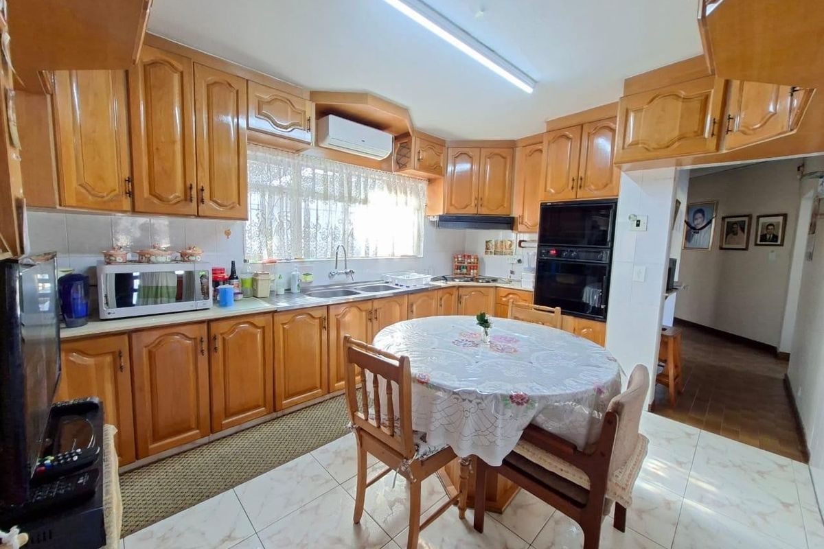 A functional kitchen featuring extensive wooden cabinetry, built-in oven, extractor fan, and tiled flooring, offering a traditional layout with ample storage space.
