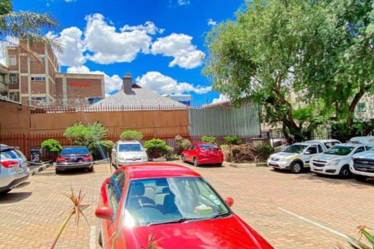 A paved outdoor parking area featuring marked bays, perimeter fencing, and mature trees, providing convenient access to the business premises.