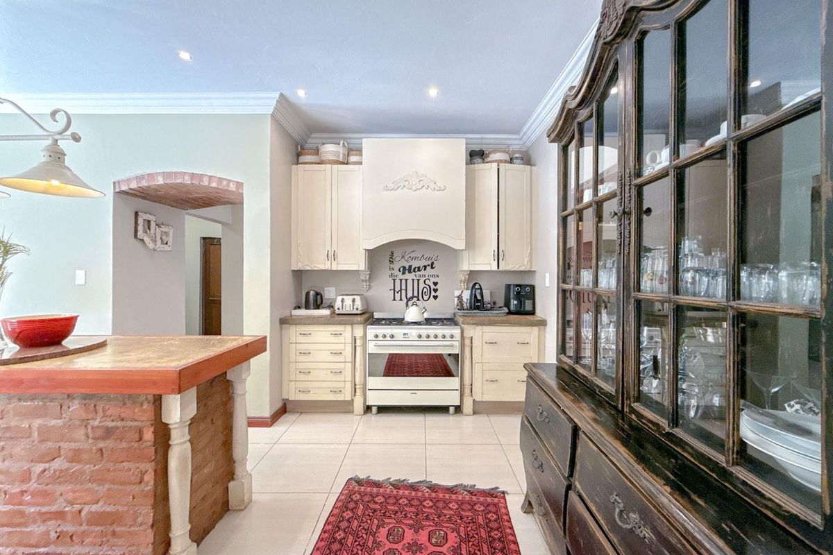 A charming kitchen featuring cream-colored cabinetry, a built-in gas stove with an extractor hood, and a rustic brick-base kitchen island.