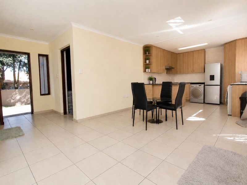 Open-plan living and kitchen area featuring tiled flooring, light wood cabinetry, and direct access to an outdoor space.
