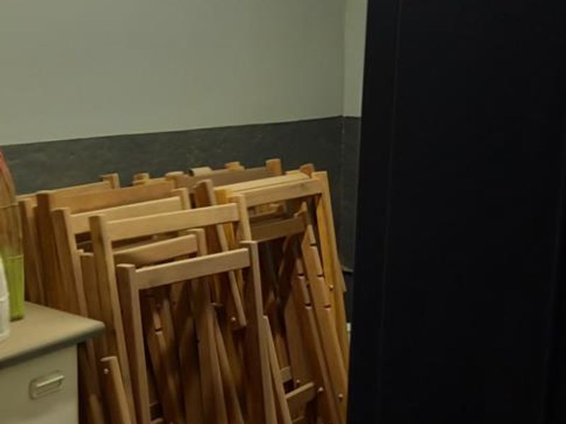 A utility space featuring tiled flooring, built-in cabinetry, and overhead fluorescent lighting, currently used for storage.