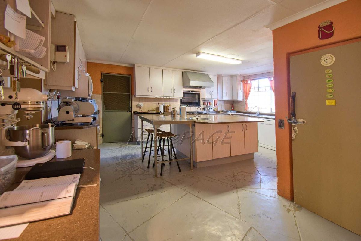 A dated kitchen featuring a central island, built-in oven, extractor fan, and ample cabinetry, requiring cosmetic updates to modernize the space.
