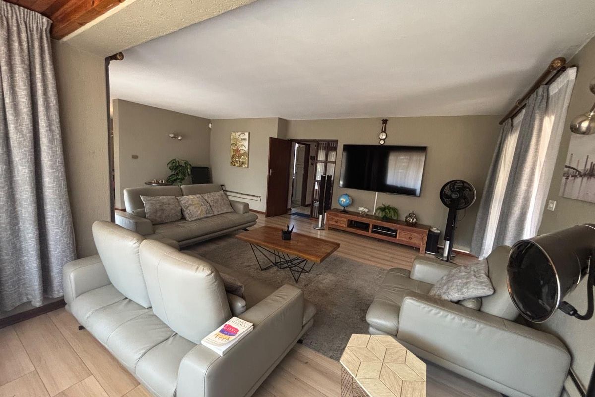 Spacious living room featuring light-toned laminate flooring, timber ceiling accents, and neutral wall finishes, providing a comfortable and functional family living space.