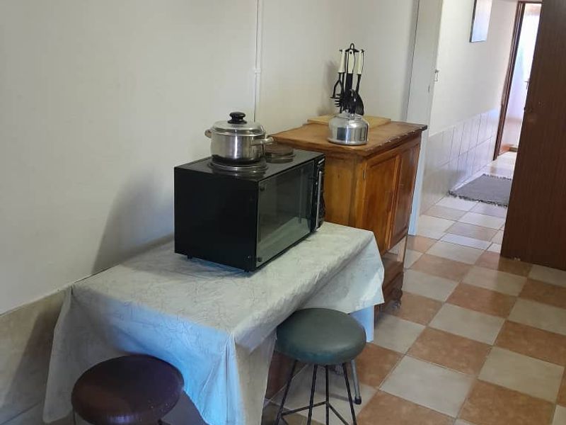 A functional utility or scullery area featuring tiled flooring and basic lighting, suitable for secondary kitchen tasks or storage.