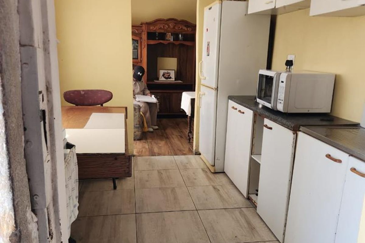 A functional kitchen space featuring tiled flooring, built-in cabinetry, and laminate countertops, currently showing signs of wear and requiring cosmetic updates.