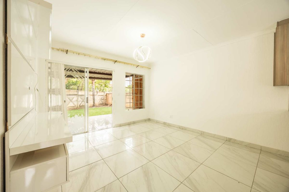 Bright and spacious living area featuring modern marble-look tiled flooring, built-in cabinetry, and direct access to the rear patio through a sliding glass door.