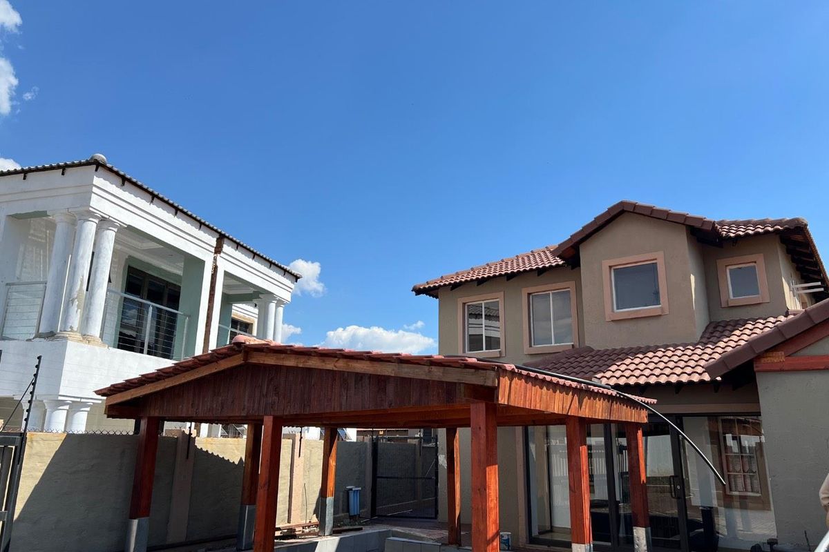 Rear view of the property featuring a timber pergola structure over a pool area with tiled finishes and adjacent residential building.