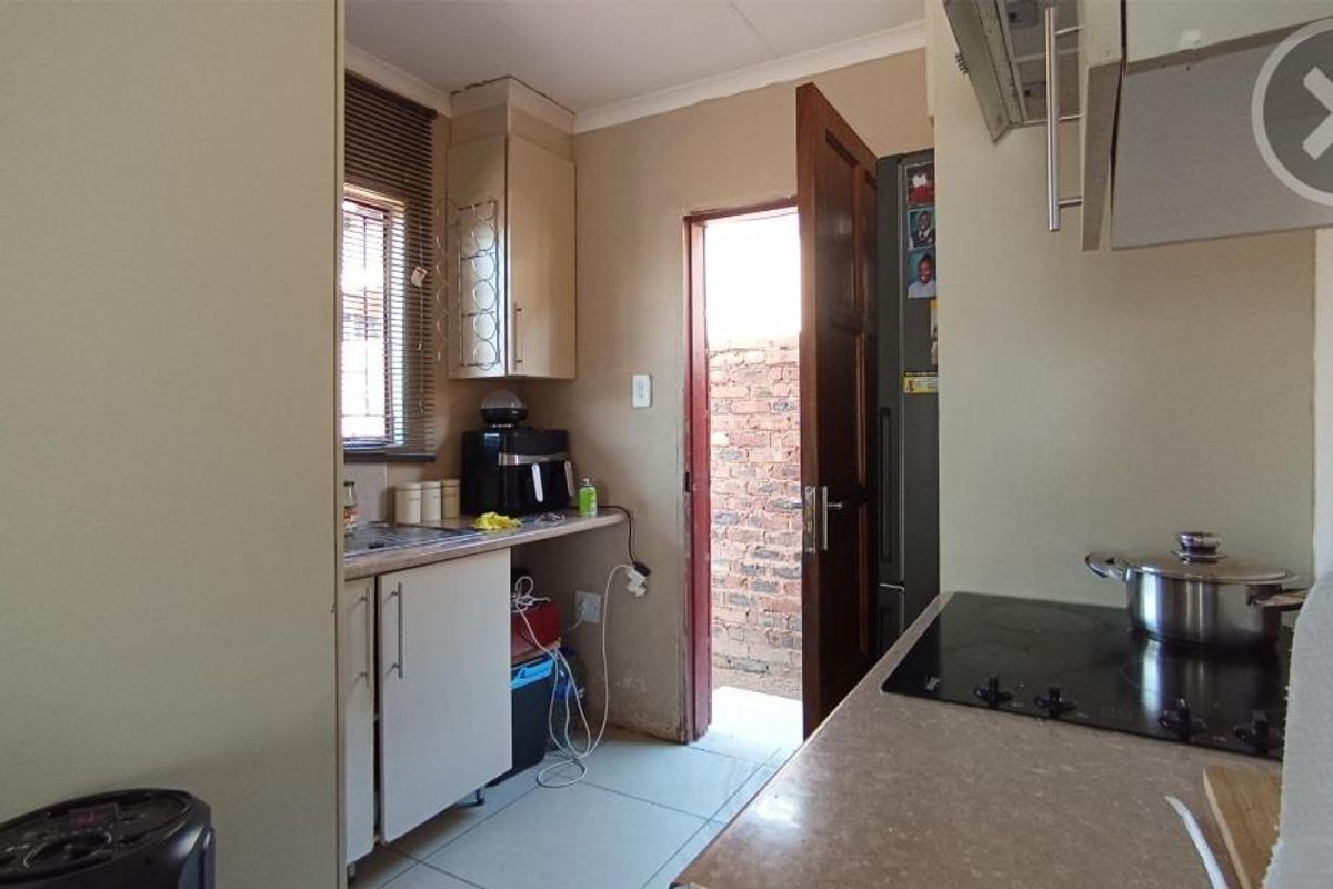 A functional kitchen featuring built-in cabinetry, a ceramic hob, and direct access to an exterior area.