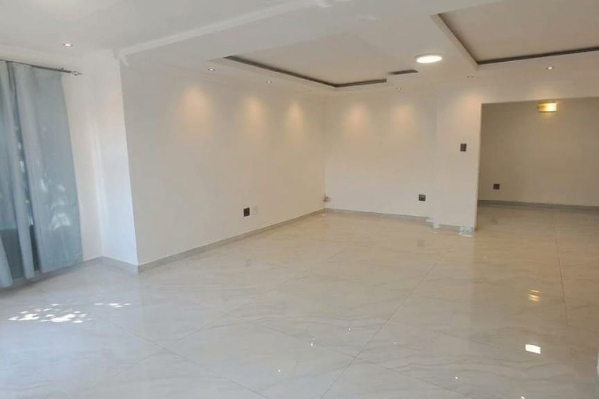 A spacious, empty living area featuring modern tiled flooring, recessed ceiling lighting, and a clean, neutral aesthetic ready for personalization.
