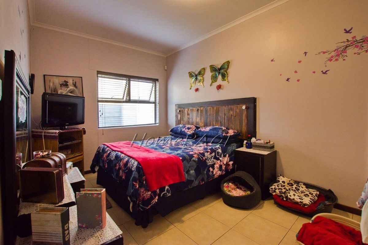 A standard bedroom featuring tiled flooring, a window with fitted blinds, and neutral wall finishes.
