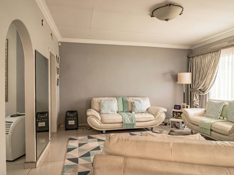 A comfortable living room featuring tiled flooring, an arched doorway, and crown molding, providing a neutral base for interior design updates.