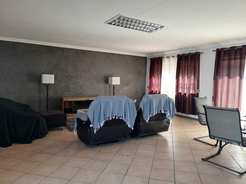 Spacious living area featuring tiled flooring, a textured feature wall, and recessed fluorescent lighting, offering a versatile space for relaxation.
