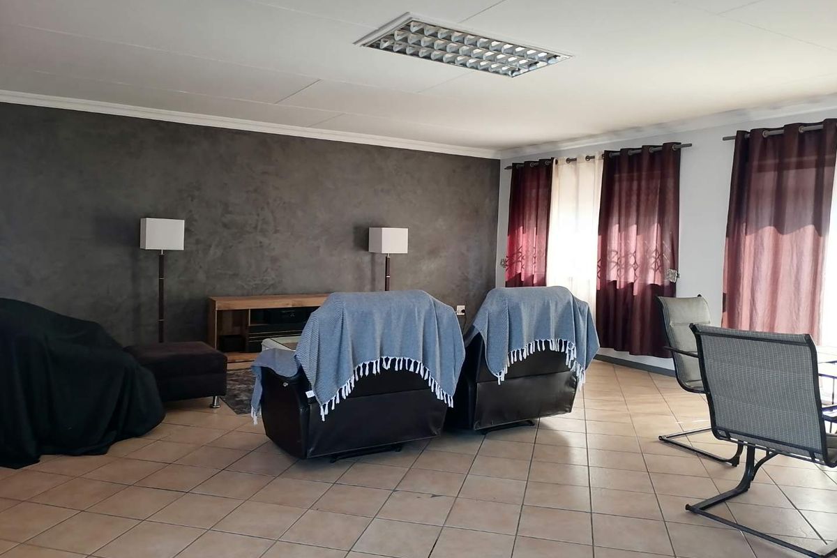 Spacious living area featuring tiled flooring, a textured feature wall, and recessed fluorescent lighting, offering a versatile space for relaxation.