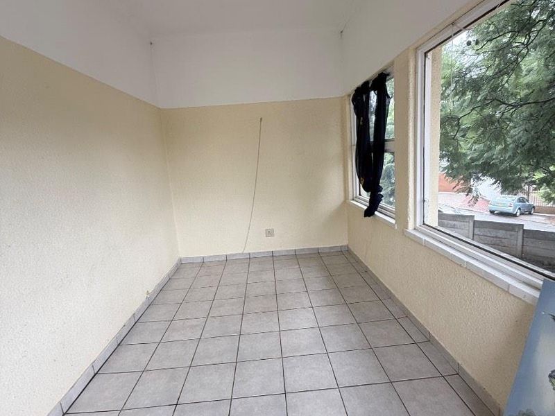 An enclosed sunroom or patio area featuring tiled flooring and large windows, offering a bright, versatile space ready for renovation or staging.