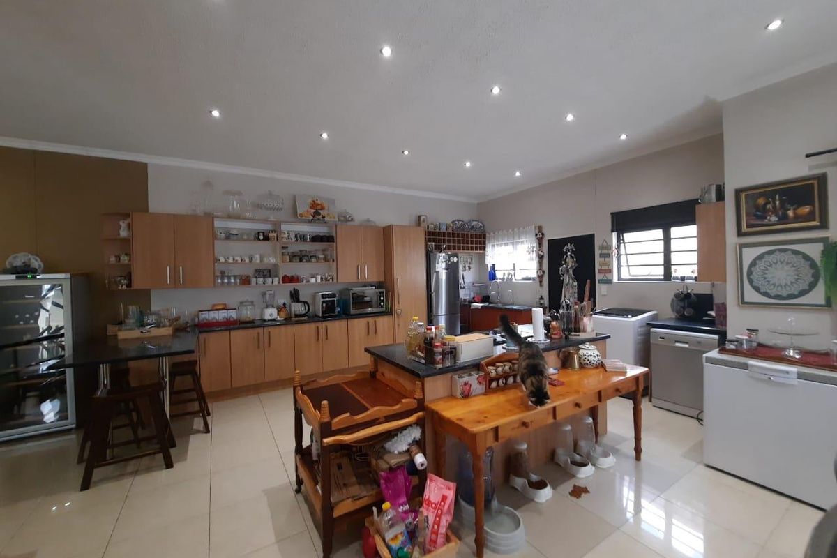 Spacious kitchen featuring light wood cabinetry, dark granite countertops, a central island, recessed ceiling lighting, and tiled flooring throughout.