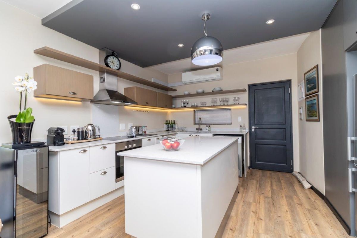 Modern kitchen featuring a central island, sleek cabinetry, integrated stainless steel appliances, and a stylish recessed ceiling detail with downlighting.