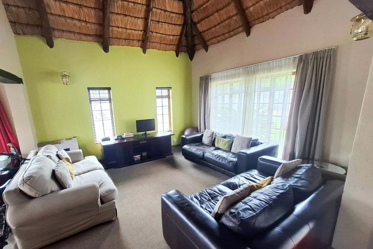 Spacious living room featuring a high vaulted thatched ceiling with exposed timber beams and large glass sliding doors providing natural light.