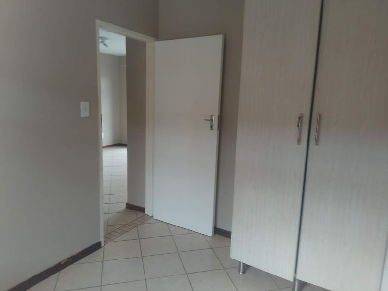 A functional bedroom featuring built-in cupboards and neutral tiled flooring, offering a clean and versatile space ready for personalization.