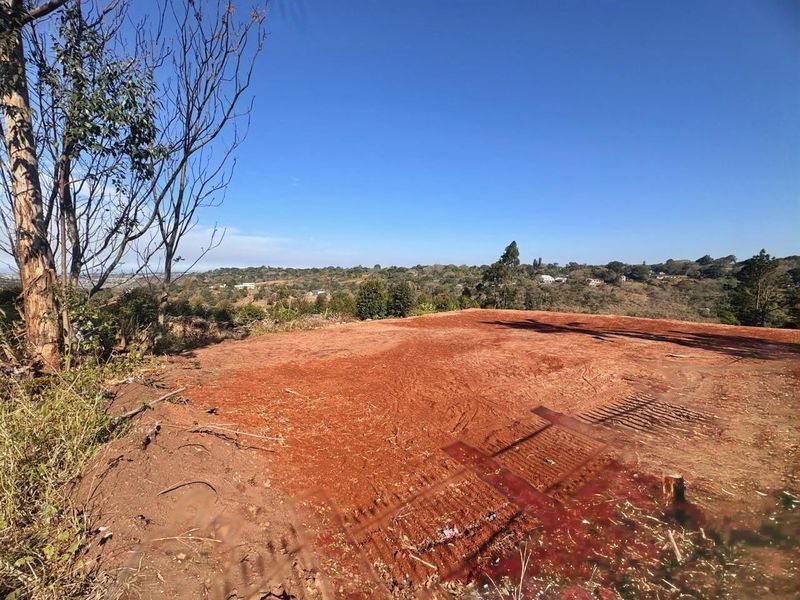 A view of a cleared residential plot of land featuring natural terrain and expansive landscape views.