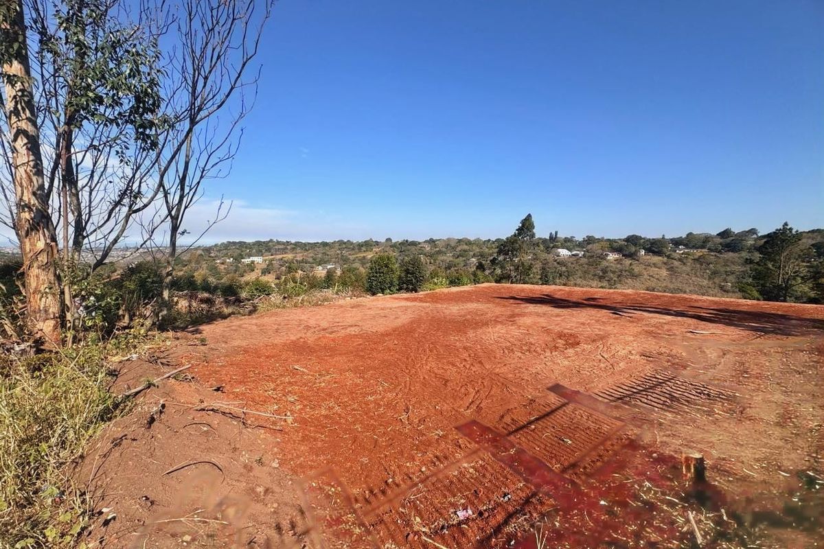 A view of a cleared residential plot of land featuring natural terrain and expansive landscape views.