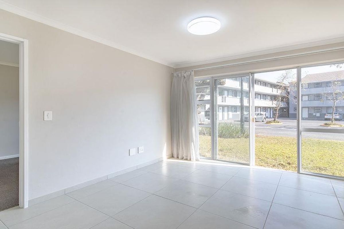 Bright and spacious living area featuring large sliding glass doors, neutral tiled flooring, and clean finishes, offering a versatile space for modern living.