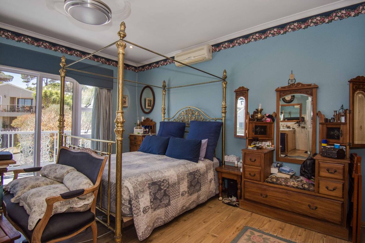 Spacious bedroom featuring timber flooring, a split-system air conditioner, and sliding glass doors providing access to an outdoor balcony area.