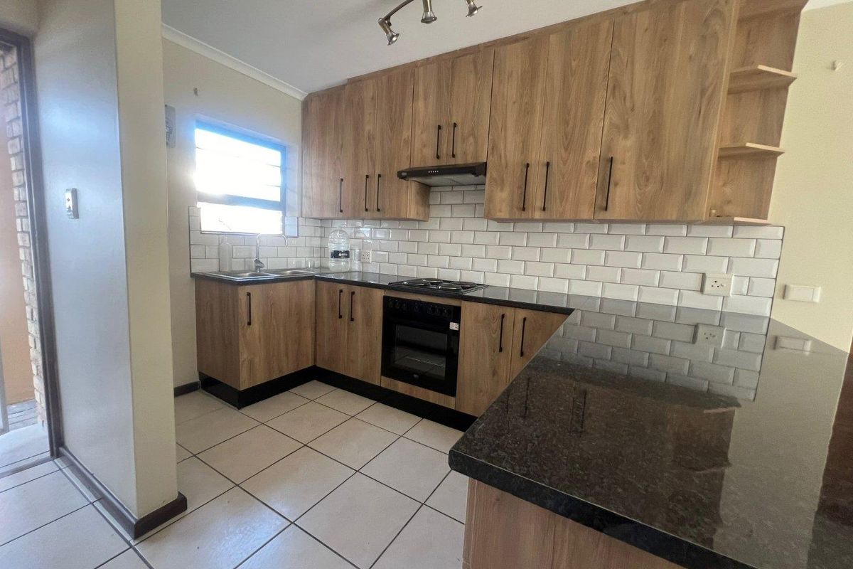 Modern kitchen featuring wood-finish cabinetry, granite countertops, subway tile backsplash, and integrated appliances, offering a clean and functional workspace.