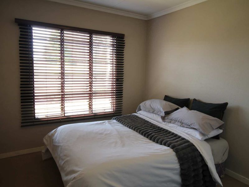 A neutrally painted bedroom featuring fitted venetian blinds and coving, providing a clean and functional space.