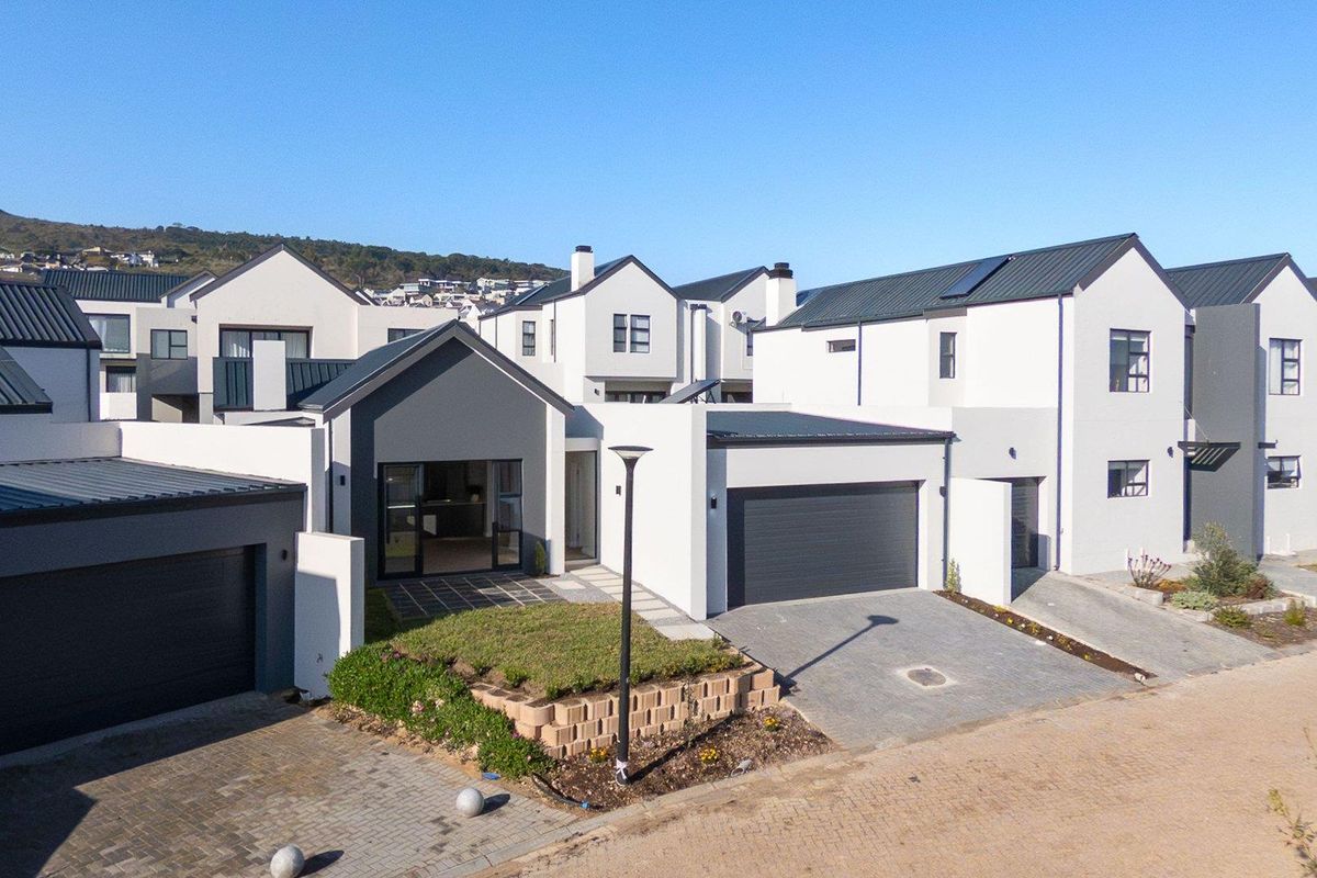 An elevated view of a modern residential property featuring contemporary architecture, paved driveways, integrated garages, and landscaped garden areas.