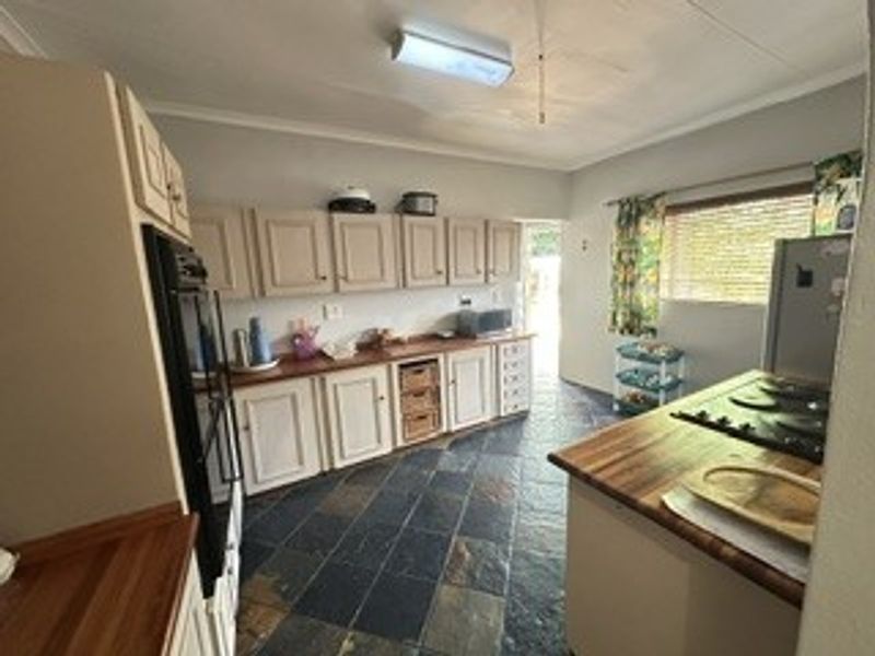 A functional kitchen featuring wooden countertops, built-in cabinetry, a built-in oven, and durable slate tile flooring.