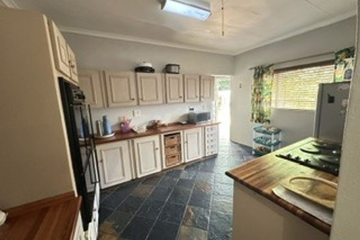 A functional kitchen featuring wooden countertops, built-in cabinetry, a built-in oven, and durable slate tile flooring.
