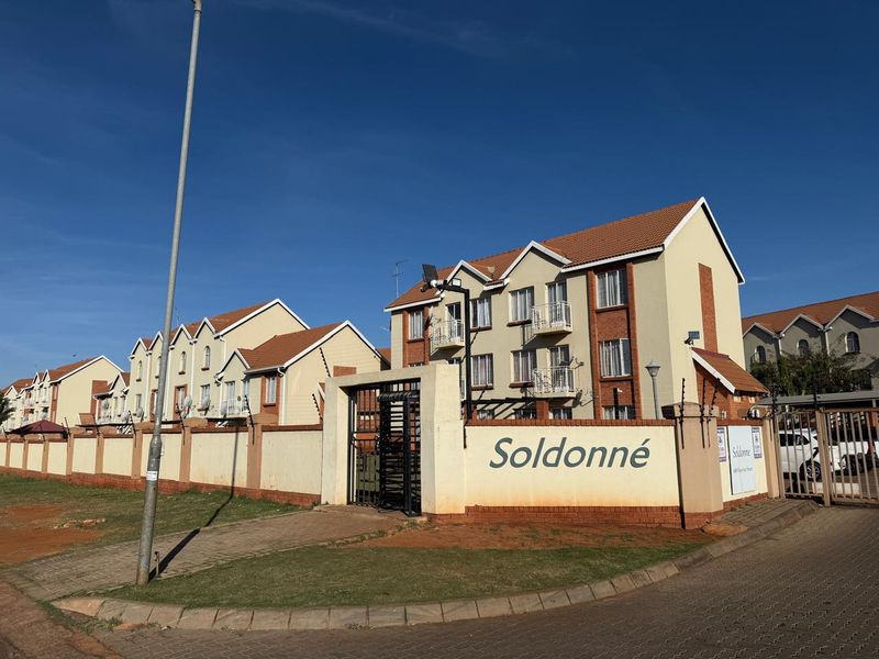 Exterior view of the Soldonné apartment complex, featuring multi-story residential buildings with tiled roofs, balconies, and secure perimeter walling.