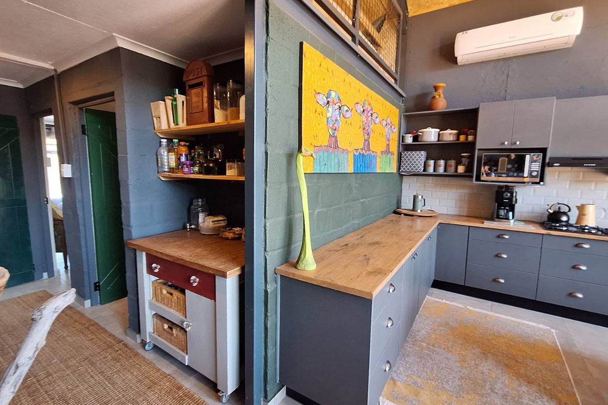 Modern kitchen featuring grey cabinetry, wooden countertops, subway tile backsplash, and a dedicated scullery area with additional storage and workspace.