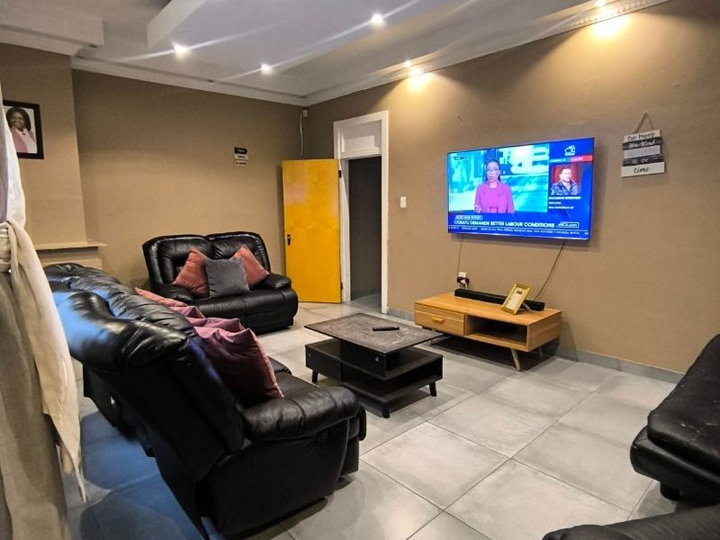 A living room featuring tiled flooring, a recessed ceiling with downlights, and neutral wall tones, providing a functional and comfortable space.