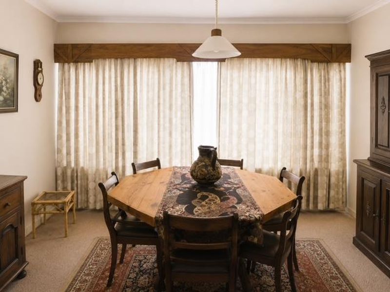 A traditional dining room featuring a wooden pelmet above the window and a central pendant light fixture.