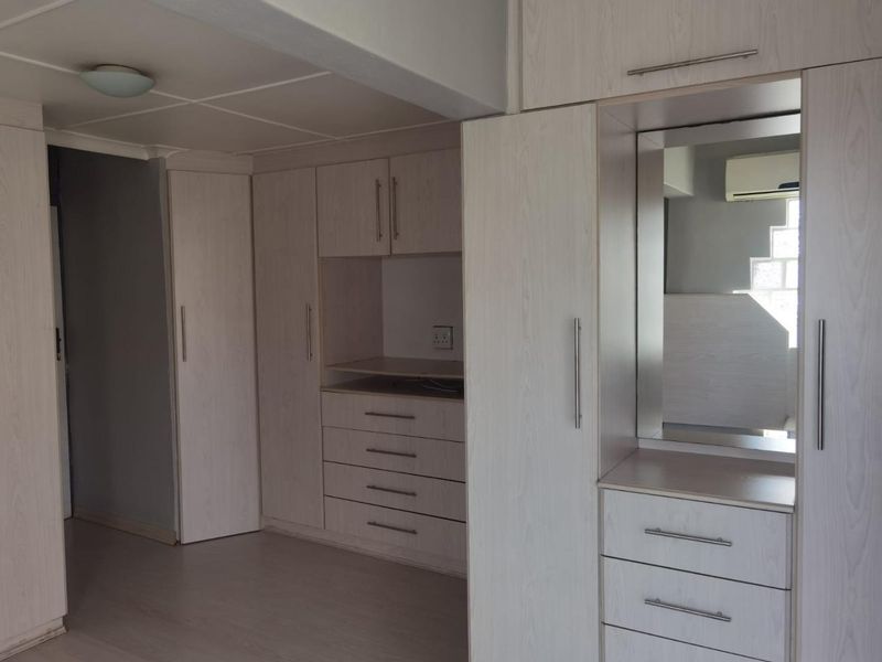 A bedroom featuring extensive light-wood built-in cabinetry, including a vanity area with a mirror and integrated storage drawers.