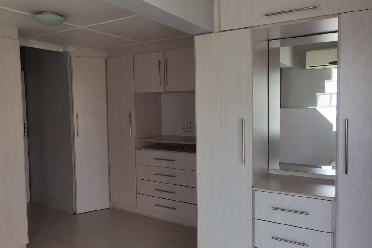 A bedroom featuring extensive light-wood built-in cabinetry, including a vanity area with a mirror and integrated storage drawers.